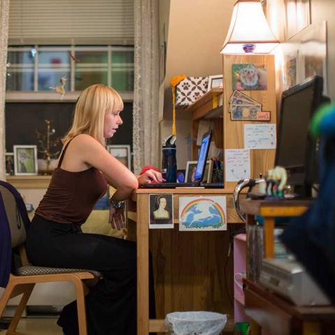 A student at the desk in their dorm room
