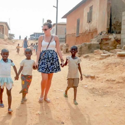 A woman walks with children through their town